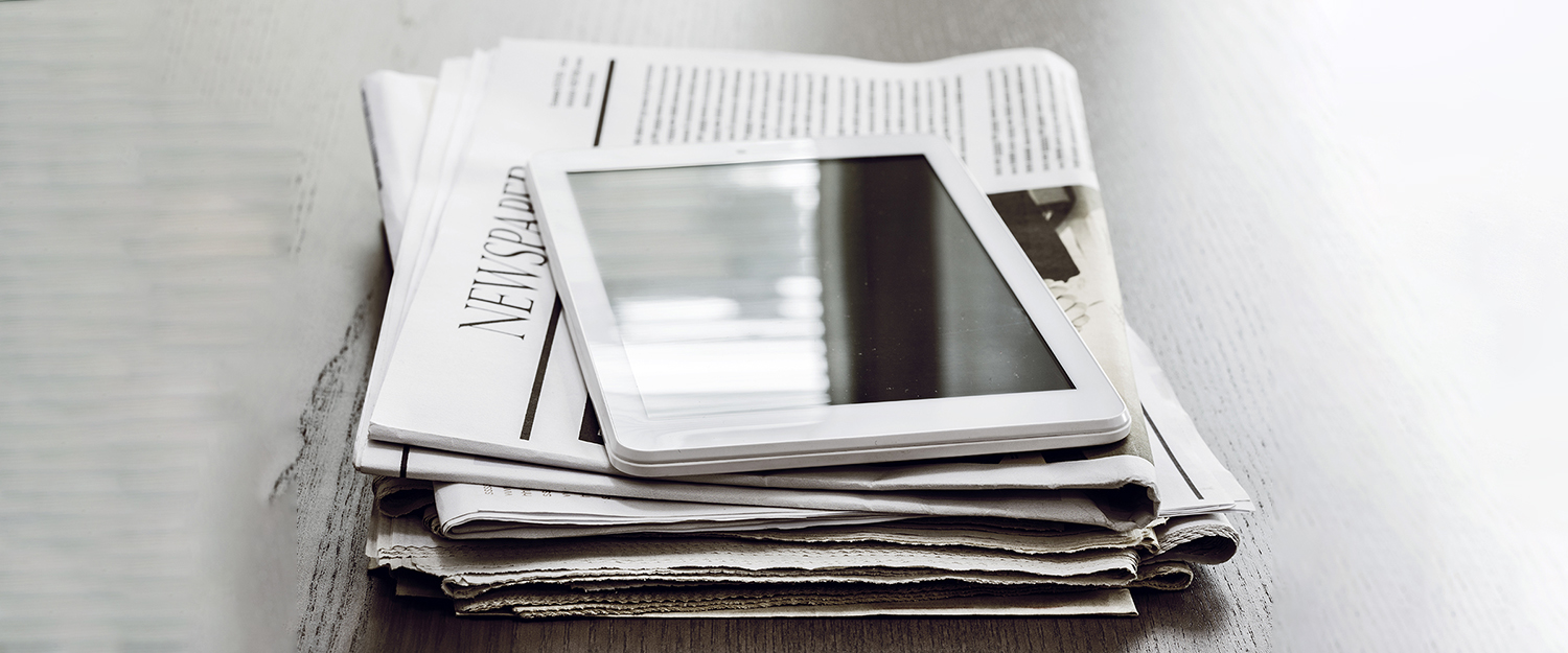 Newspaper and digital tablet on wooden table