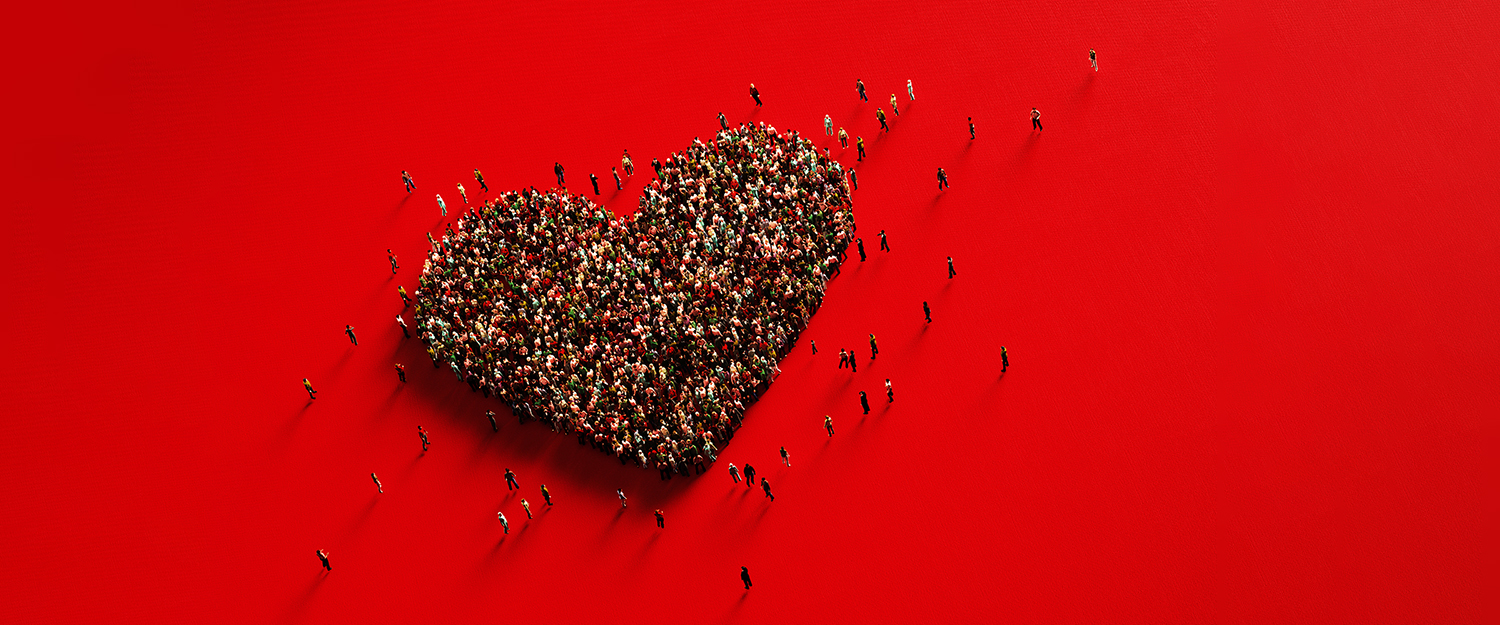 Human Crowd Forming A Big Heart Shape On Red Background: Love and Donation Concept